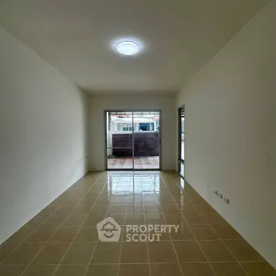 Spacious empty living room with tiled floor and large sliding doors leading to a balcony.