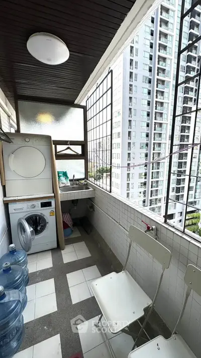 Charming balcony with laundry area and city view in modern apartment building.