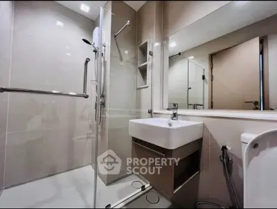 Modern bathroom with glass shower and sleek fixtures in contemporary apartment.