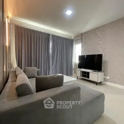 Modern living room with sleek gray sofa and large TV, perfect for relaxation.