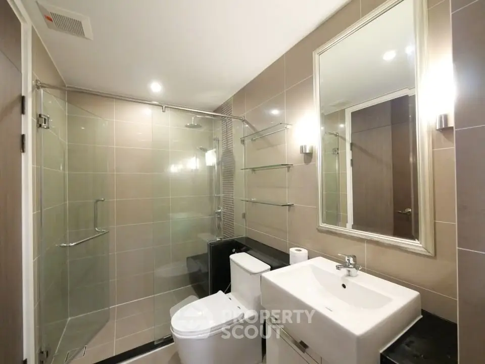 Modern bathroom with glass shower and sleek fixtures in a contemporary apartment.