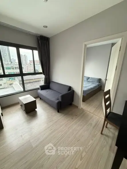 Modern apartment living room with city view and adjacent bedroom.