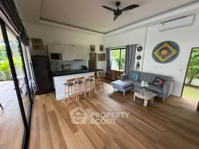 Spacious open-plan living room with modern kitchen and garden view, featuring stylish decor and natural light.