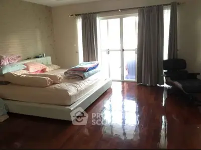 Spacious bedroom with polished wooden floors and large windows for natural light.