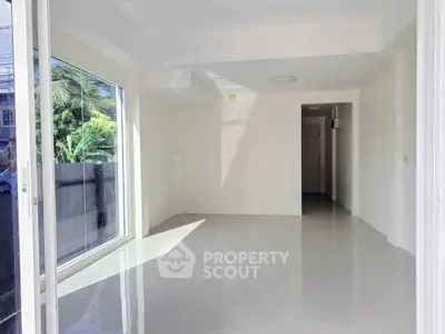 Bright and spacious empty room with large window and glossy floor tiles, perfect for customization.