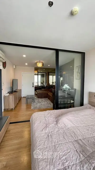 Spacious modern apartment with open layout, featuring a cozy bedroom and stylish living area separated by glass doors.