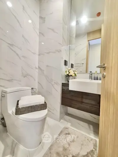 Modern bathroom with sleek design, featuring a stylish sink and elegant marble walls.