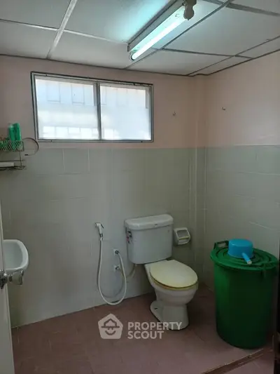 Simple bathroom with basic fixtures and natural light from window.