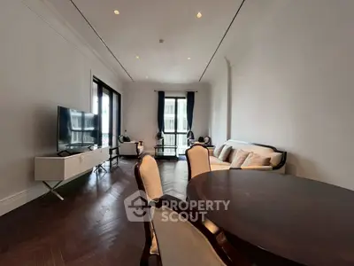 Elegant living room with dark wood flooring, stylish furniture, and large windows offering natural light.