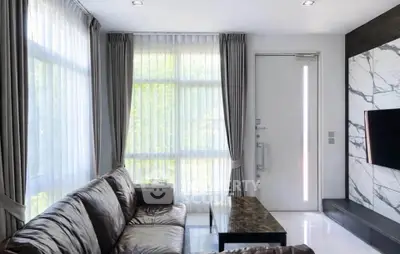 Modern living room with leather sofa, marble accents, and large windows for natural light.