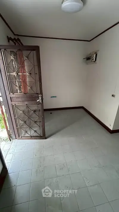 Compact room with tiled floor and security door, ideal for storage or utility use.