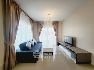 Elegant living room with chandelier, modern sofa, and large windows for natural light.