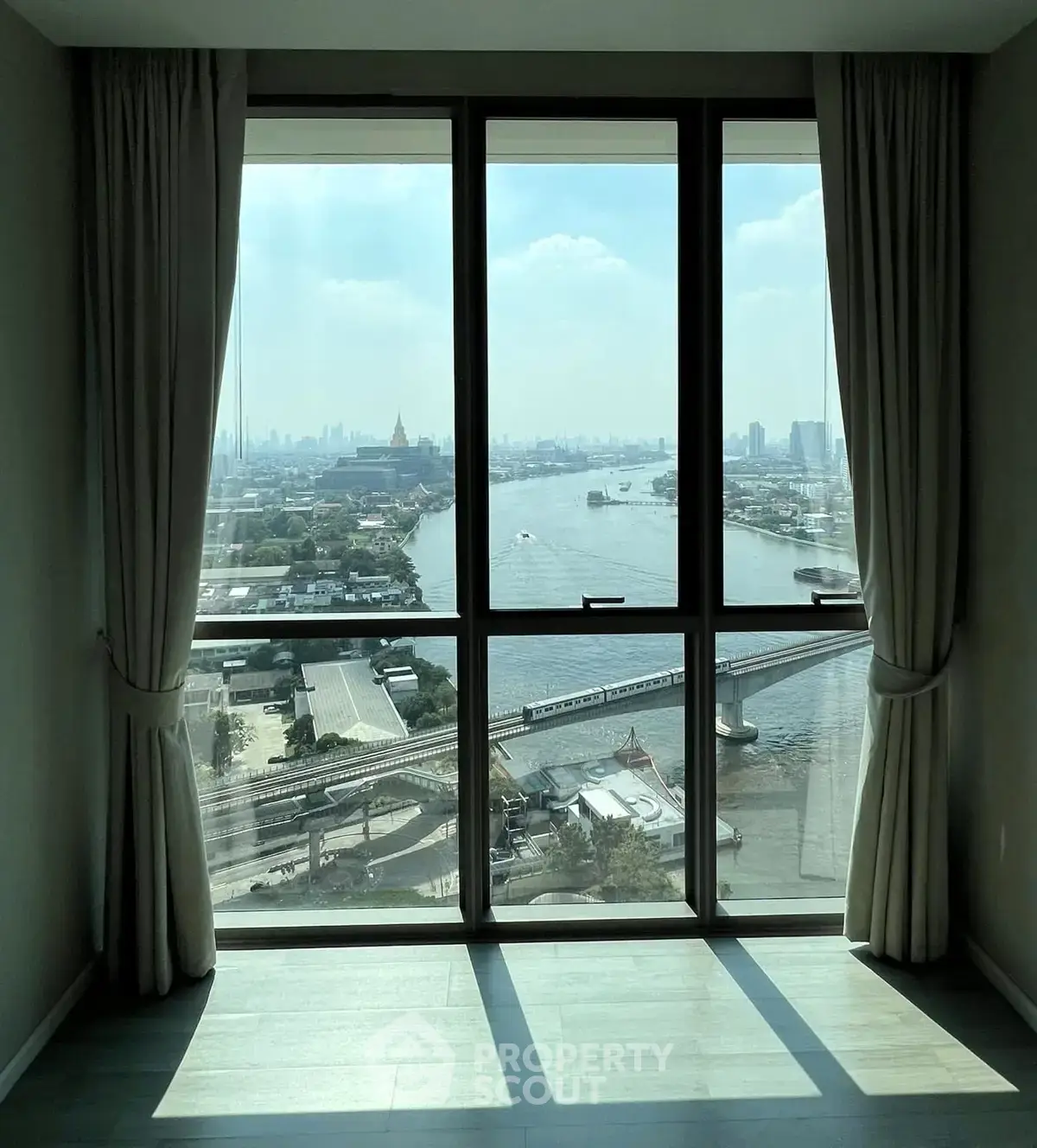 Stunning river view from a high-rise apartment window with cityscape in the background.