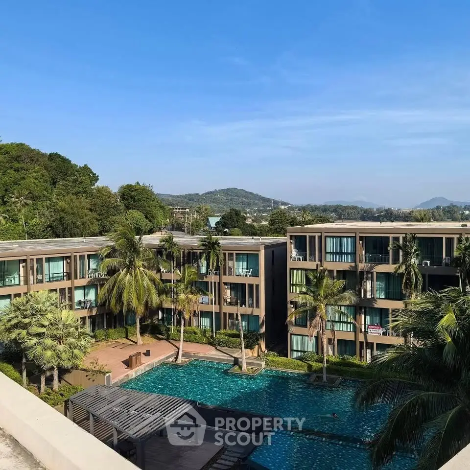 Luxurious apartment complex with pool and scenic mountain views, surrounded by lush greenery.