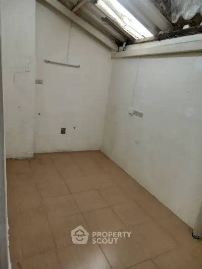 Compact storage room with tiled flooring and sloped ceiling, ideal for small spaces.