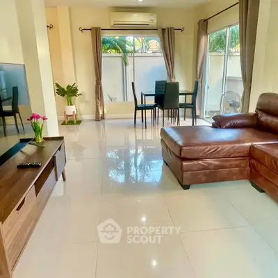 Spacious living room with modern leather sofa and dining area, perfect for relaxation and entertaining.