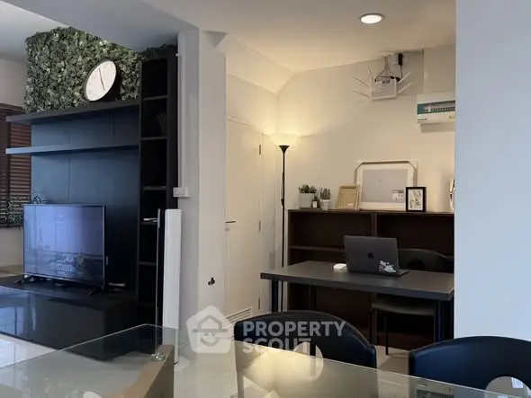 Modern living room with stylish decor and workspace, featuring a TV and air conditioning.