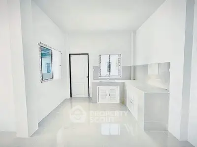 Bright minimalist kitchen with sleek white cabinetry and tiled floor