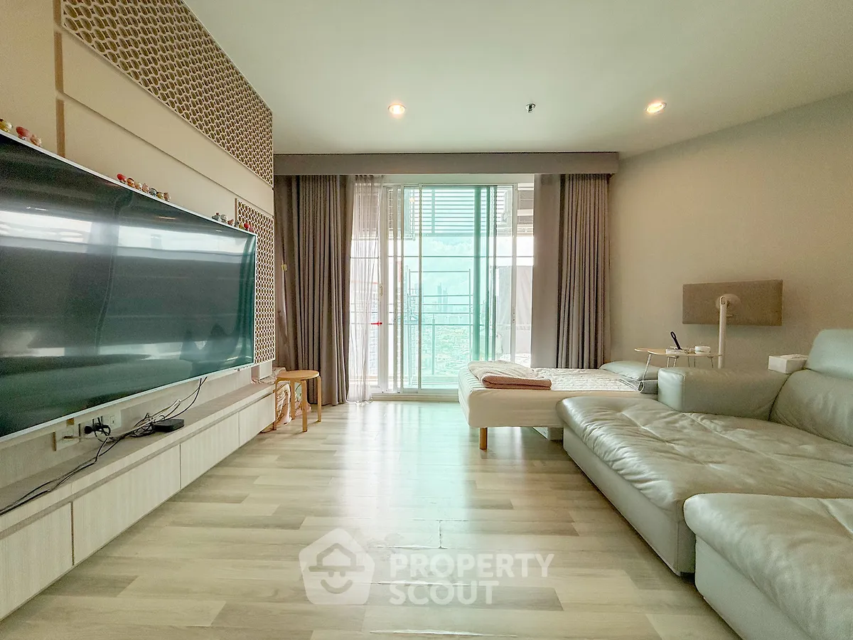 Spacious modern living room with large TV and balcony view