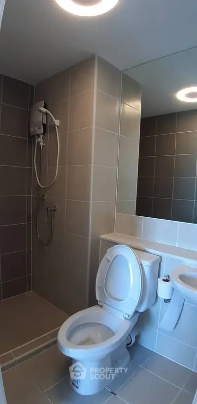 Modern bathroom with shower and toilet in sleek tile design.