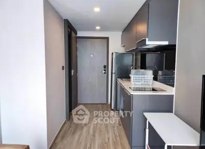Modern kitchen with sleek cabinetry and stainless steel appliances in a compact apartment.