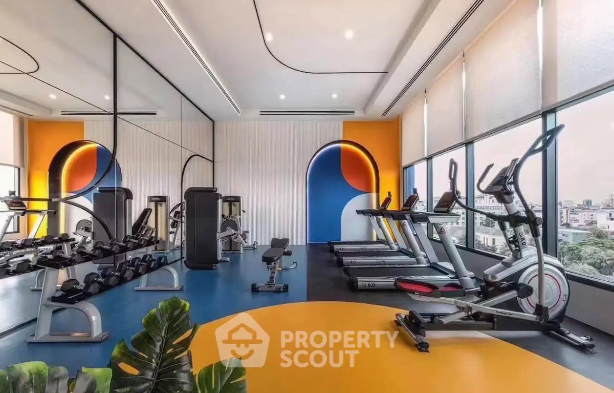 Modern gym with vibrant decor and city view, featuring state-of-the-art fitness equipment.