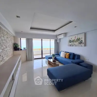 Spacious modern living room with ocean view and stylish blue sofa