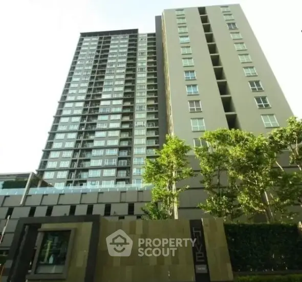 Modern high-rise residential building with lush greenery and sleek design.