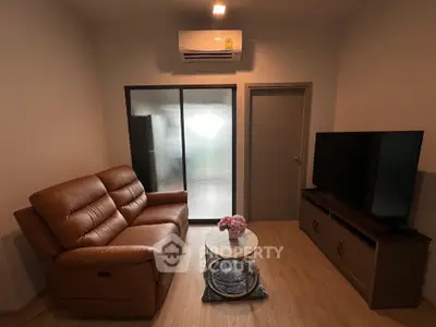Cozy living room with leather sofa and large TV, perfect for relaxation.