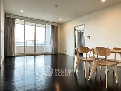 Spacious modern living room with wooden flooring and large windows leading to balcony.