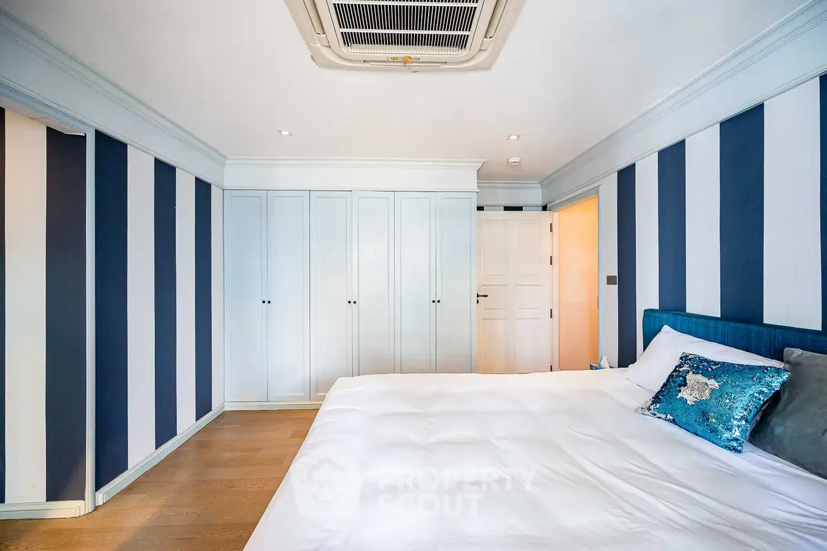 Luxurious bedroom with stylish striped walls and plush bedding in modern apartment.