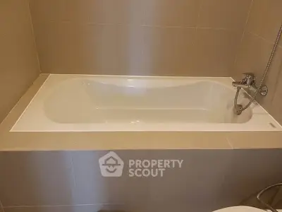 Modern bathroom with sleek bathtub and neutral tile design.