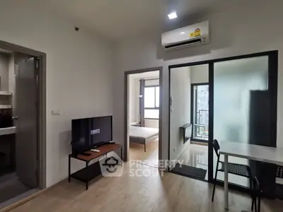 Modern apartment interior with open living room and bedroom, featuring sleek furniture and air conditioning.