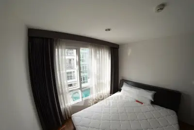 Cozy bedroom with large window and modern furnishings in a high-rise apartment.