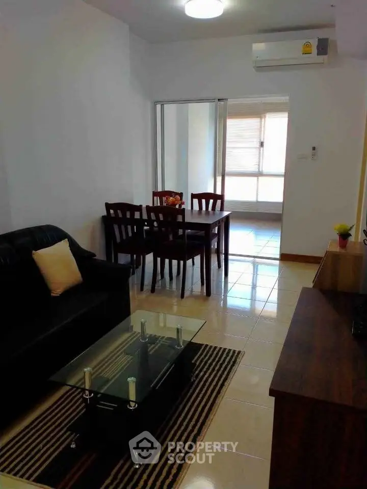 Modern living room with sleek furniture and dining area in open layout apartment.