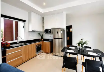 Modern kitchen with sleek cabinets, stainless steel appliances, and dining area in a stylish apartment.