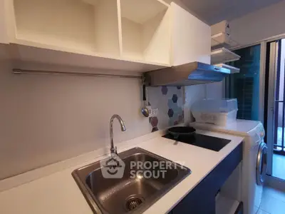 Modern kitchen with sleek design, featuring induction cooktop, stainless steel sink, and washing machine.