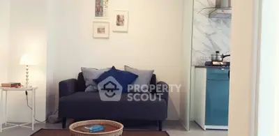 Cozy living room with modern sofa and adjacent compact kitchen area.