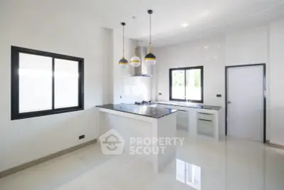 Modern kitchen with sleek design and open layout, featuring stylish pendant lights and large windows.
