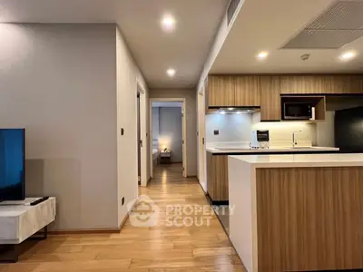 Modern open-plan kitchen with sleek wooden cabinetry and cozy hallway leading to bedroom.