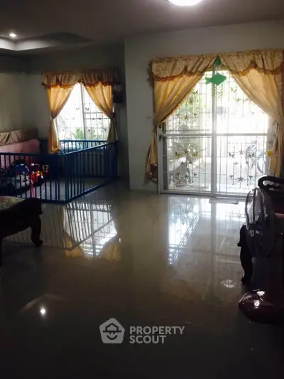 Spacious living room with large windows and elegant curtains, perfect for family gatherings.