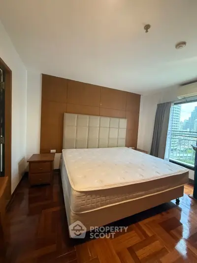 Spacious bedroom with large bed and city view, featuring elegant wooden flooring and modern design.