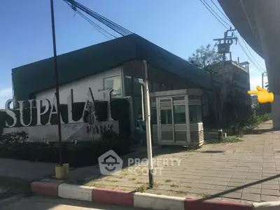 Modern building exterior with signage and paved walkway in sunny setting.