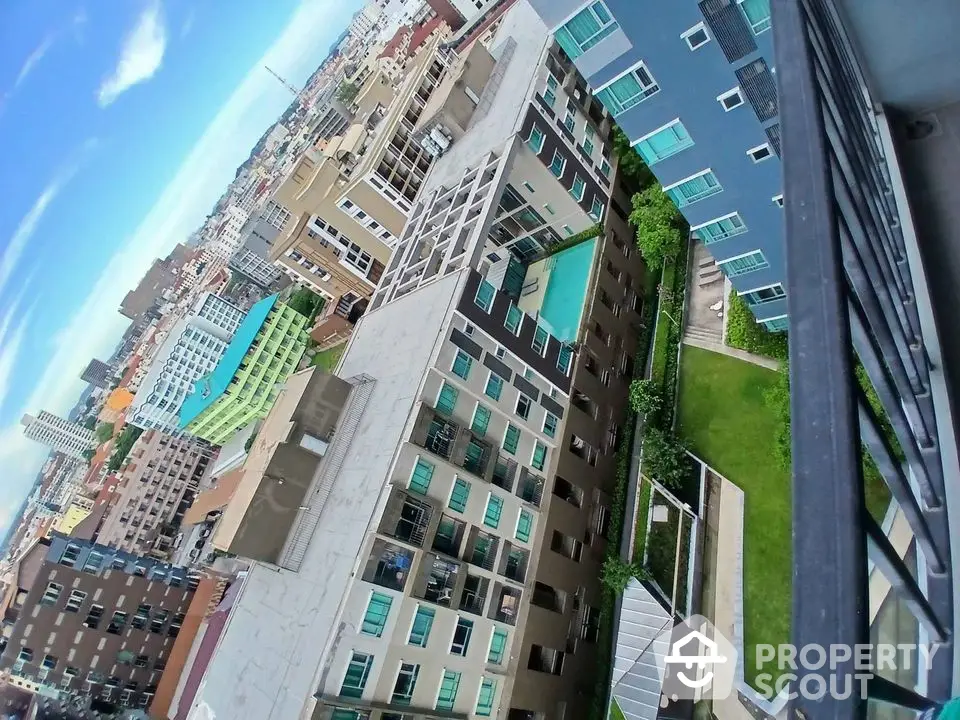 Stunning aerial view of modern urban apartment complex with rooftop pool and lush garden.