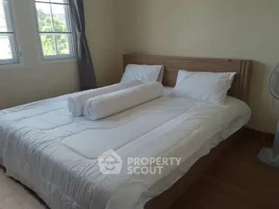 Spacious bedroom with large bed and natural light from windows, perfect for relaxation.