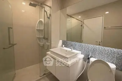 Modern bathroom with glass shower and sleek vanity in contemporary home.