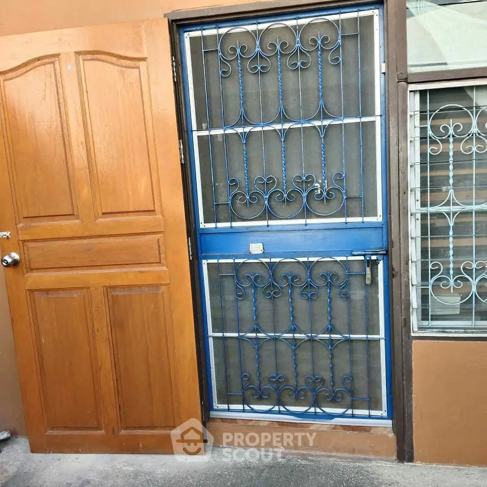 Charming entrance with wooden door and decorative metal security gate
