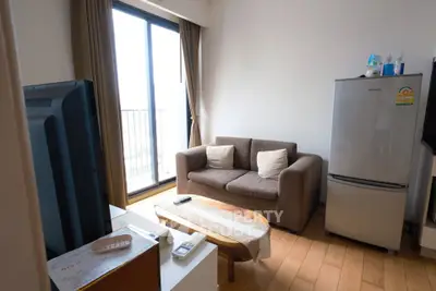 Cozy living room with sofa, fridge, and balcony view