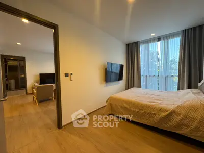 Modern bedroom with wall-mounted TV and view into cozy living area