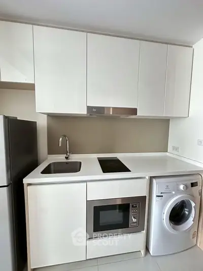Modern kitchen with sleek white cabinets, built-in appliances, and washing machine.